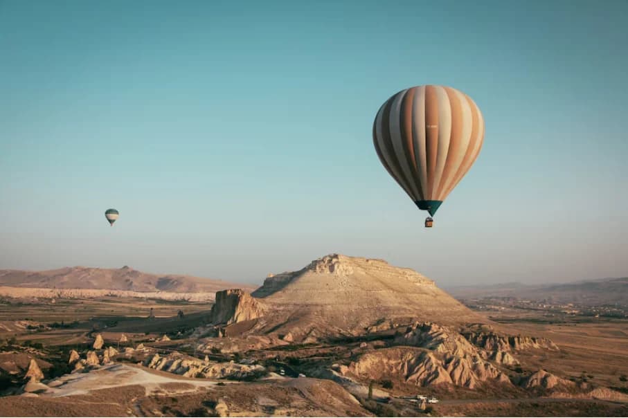 Hot air balloon flying above Uçhisar and the Cappadocia landscape
